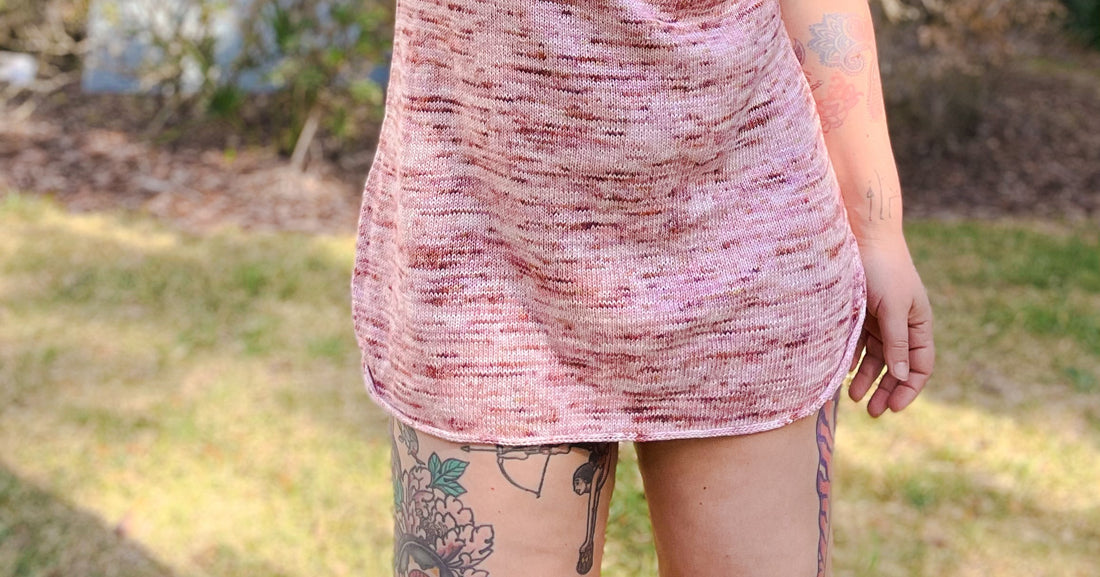 Bess, seen from the waist down, wears a light pink speckled dress, knit from her Alice tee pattern.