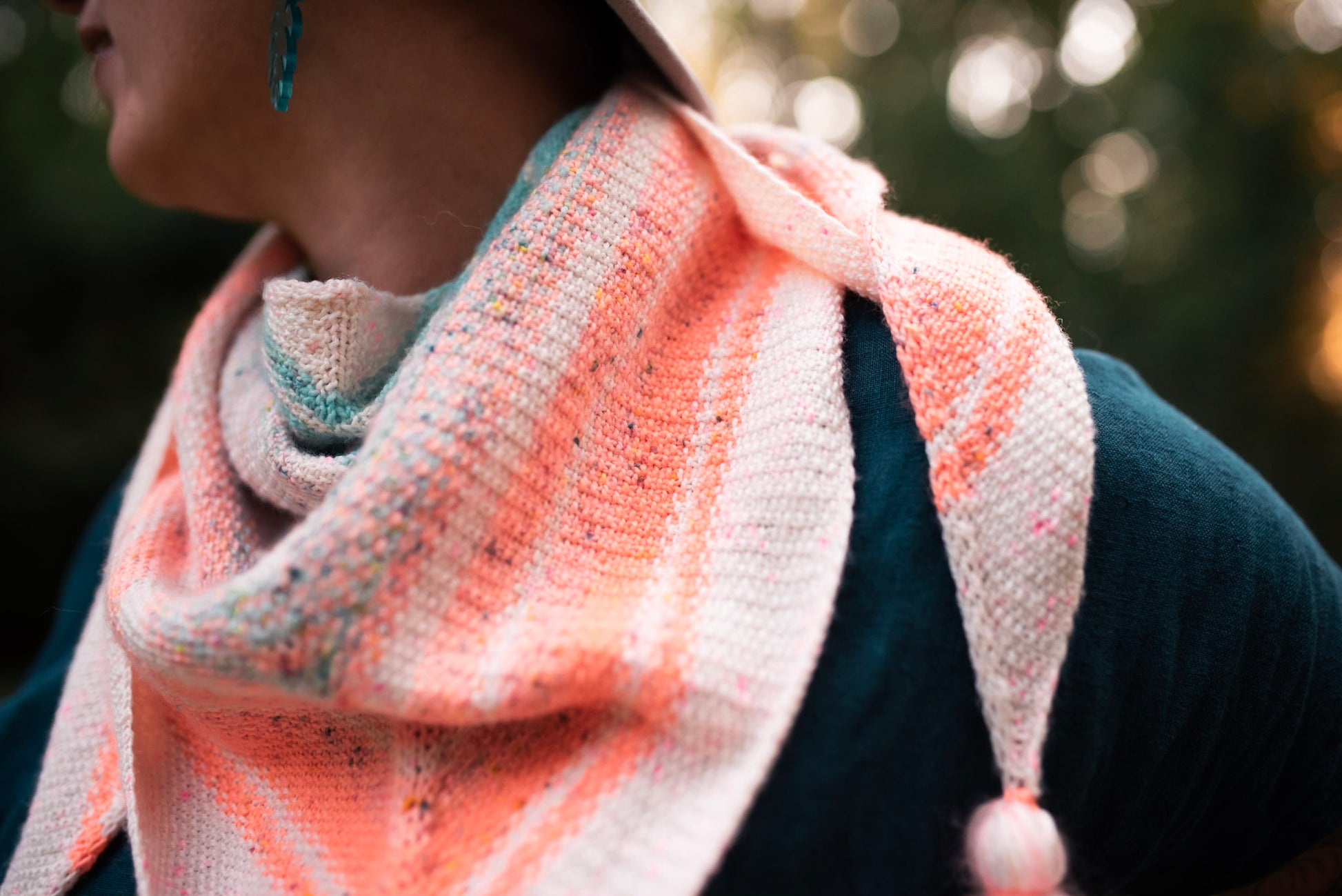 Seen up close, Jen wears a pastel shawl, knit with tassels at each end. The textured seed stitch pattern can be seen. 