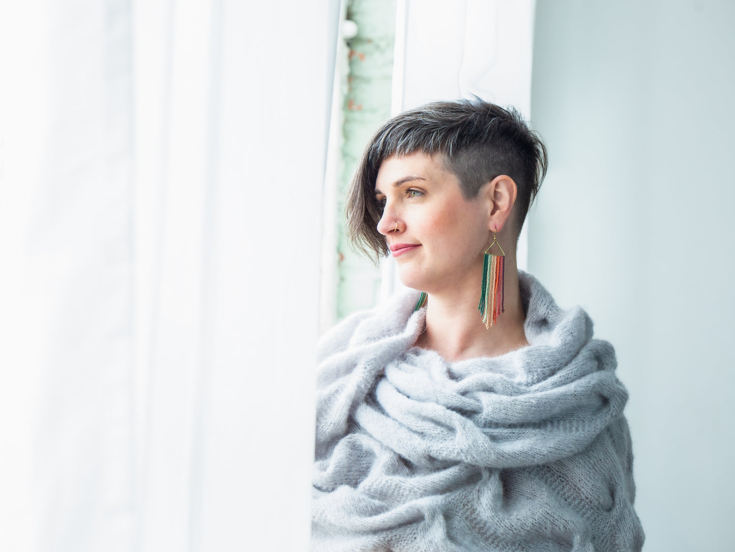 Looking off camera, Jen wears a fluffy shawl, knit with light blue yarn, wrapped around her shoulders.