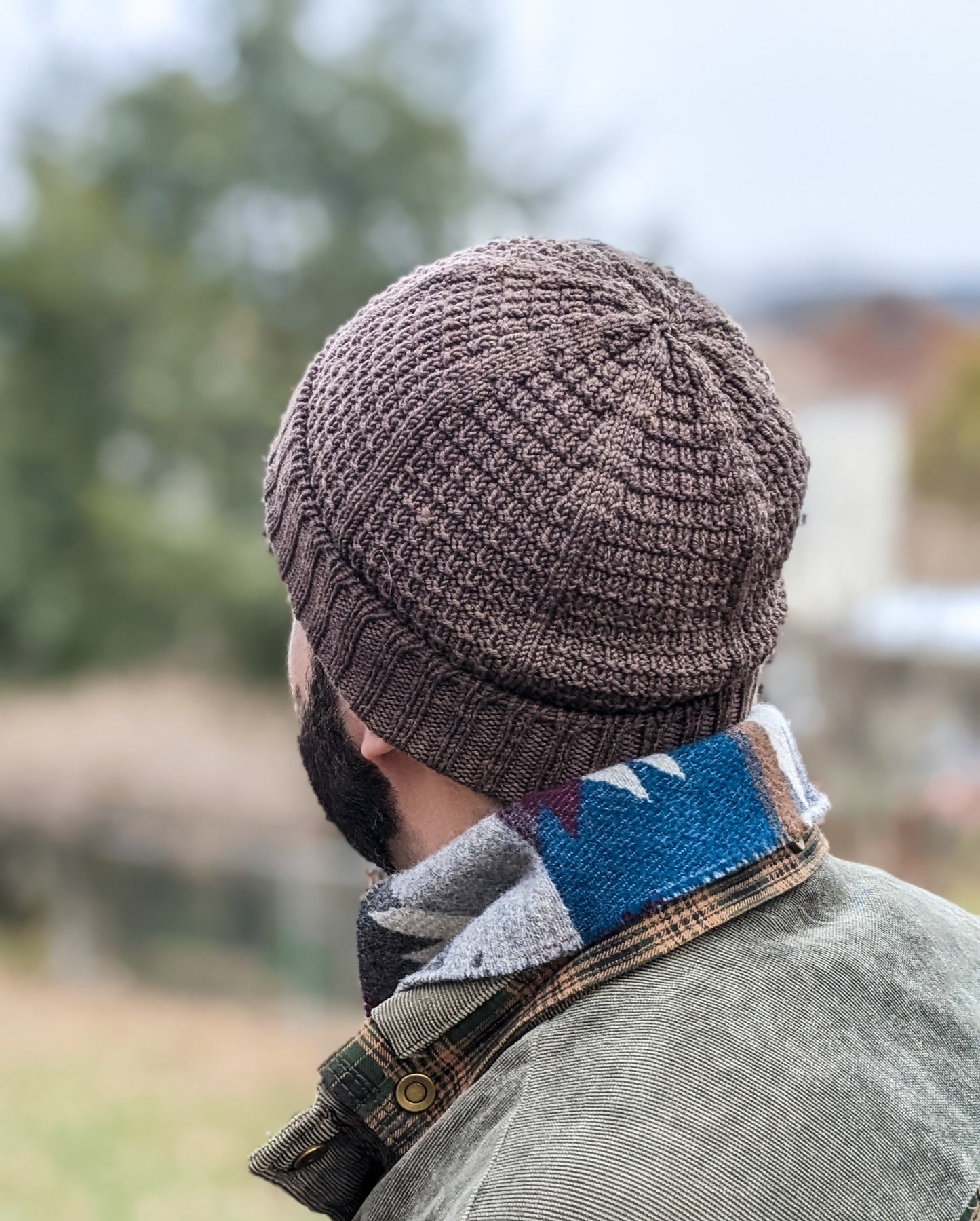 Seen from behind close up, Drew wears a brown knit beanie with a seed stitch design.