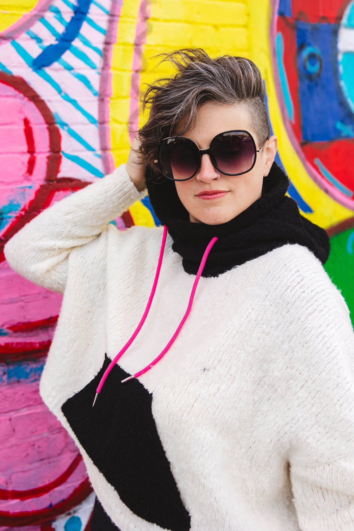 Jen wears Keeper, a super soft handknit hoodie with a bright black and white graphic colorblock effect.