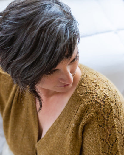 Seen from above at an angle, Jen wears a gold dolman tee, knit with leafy lace down the sleeves and eyelet lace strips coming down from the shoulder seam.