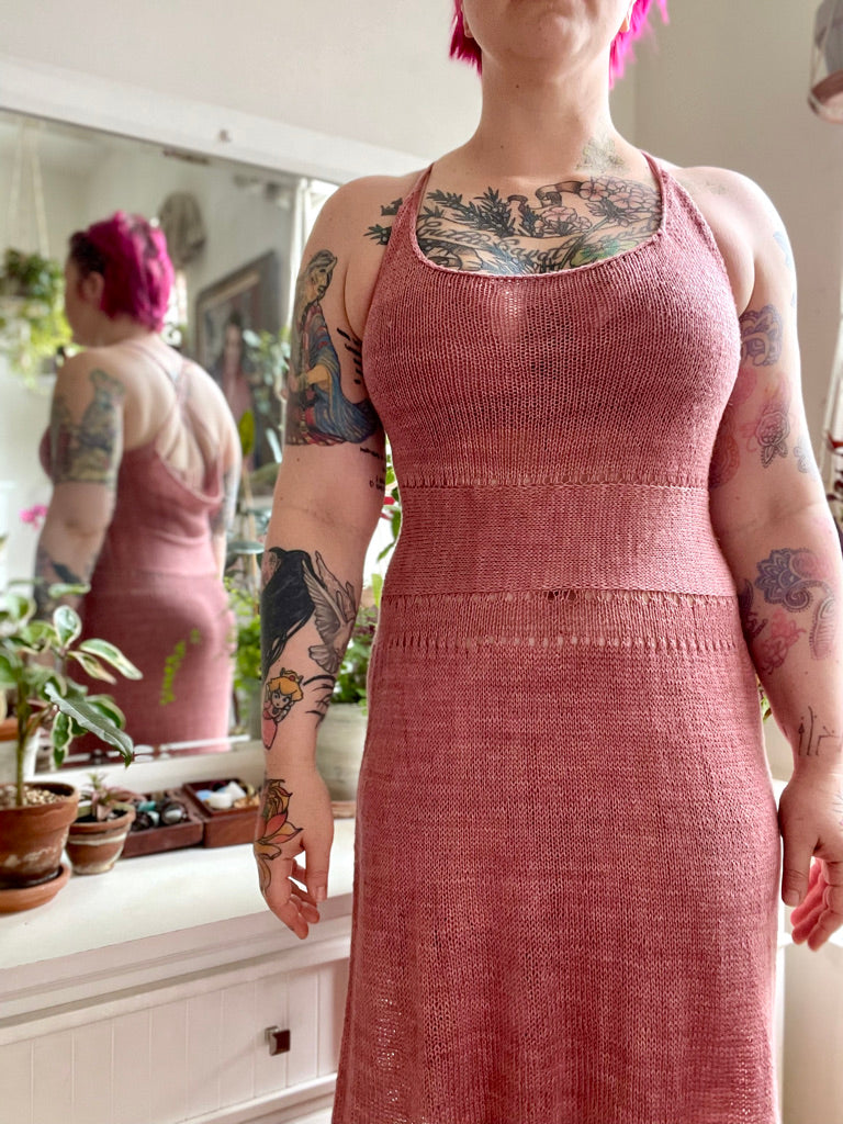 Seen from the shoulders down, Bess wears a dusty pink sleeveless dress. It's knit in silky yarn with a cinched waist.