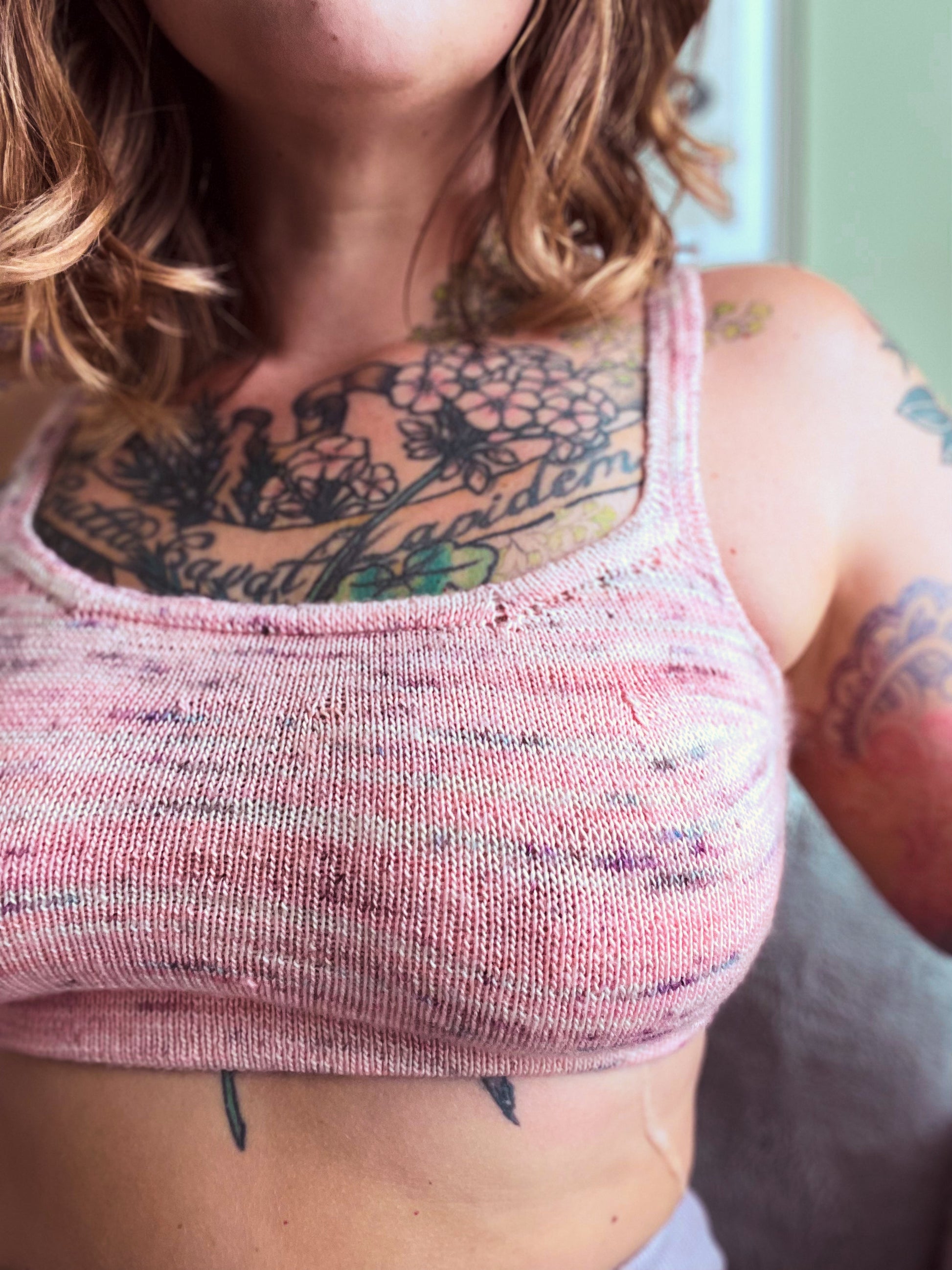 Seen close up, Bess wears a fitted bralette, knit from light pink speckled yarn.