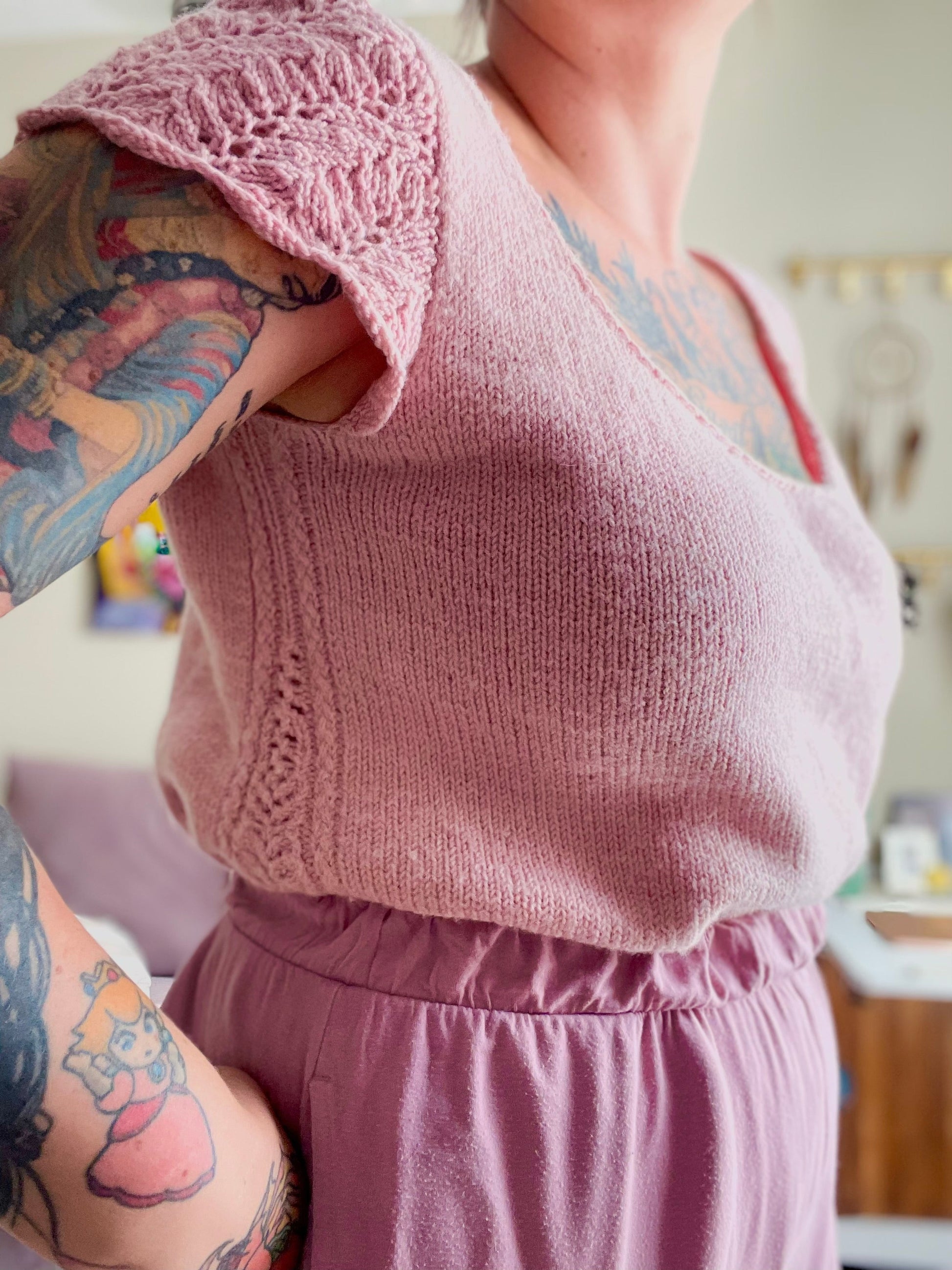 A woman stands with her hands on her hips, she is wearing a hand knit loose fitting tee with lace details. The Anna Tee is tucked into a pair of lavender pajama bottoms, accentuating the lightweight blousey nature of a wool tee with positive ease.