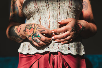 Seen from the shoulders down, bess wears a light grey chevron lace tank top with a scalloped hem, knit from the Tori Tank pattern.