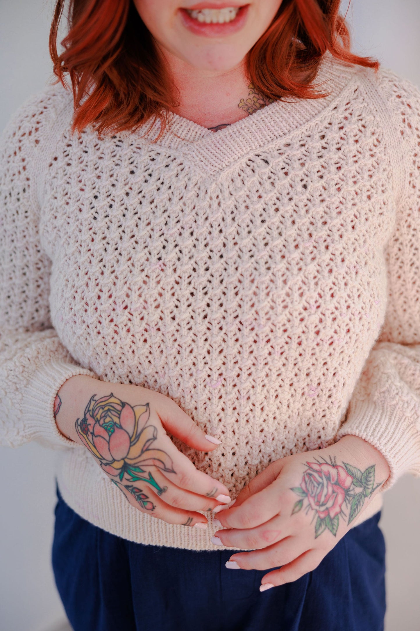 Bess wears a cream coloured lace knit sweater, the Mary raglan, with blue pants.