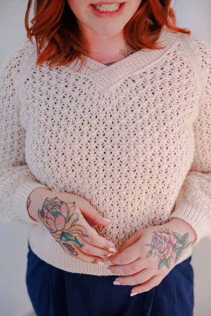 Bess wears a cream coloured lace knit sweater, the Mary raglan, with blue pants.